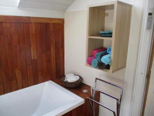Peyrieu的住宿－Chez Fabienne，带浴缸和水槽的浴室以及木墙