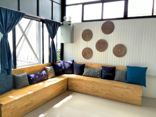 a long wooden couch in a room with windows at Lamoon Boutique Hotel in Suphan Buri