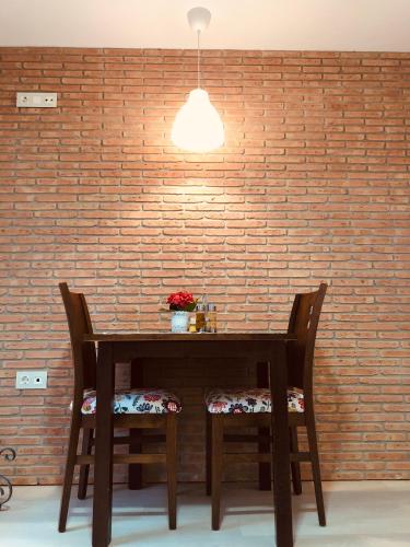 Ein Holztisch mit zwei Stühlen vor einer Backsteinmauer in der Unterkunft Duplex Archidona Centro in Archidona