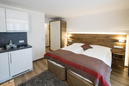 a bedroom with a large bed and a sink at B-Inn Apartments Zermatt in Zermatt