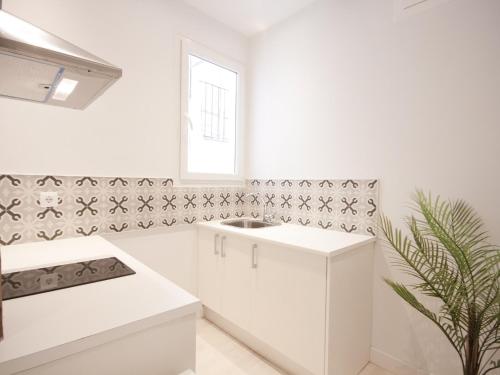uma cozinha branca com um lavatório e uma janela em Apartamento con encanto en ópera em Madri