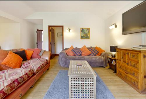 a living room with two couches and a flat screen tv at White Lodge Cottage in Guildford