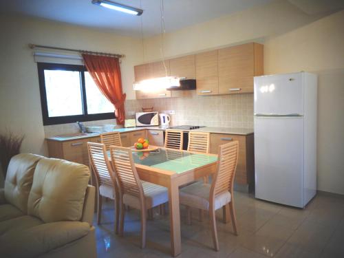 a kitchen with a table and chairs and a white refrigerator at Kyklades Resort & Spa in Paralimni