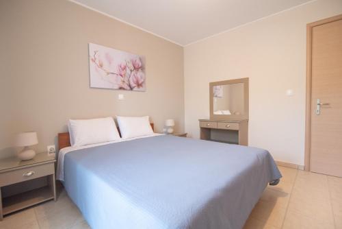 - une chambre blanche avec un lit bleu et un miroir dans l'établissement Οίνου Γη Ιθάκη - Winelandithaca, à Perakhórion