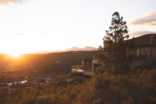 a house on a hill with the sunset in the background at Garden Route Ilita Lodge in Groot Brak Rivier