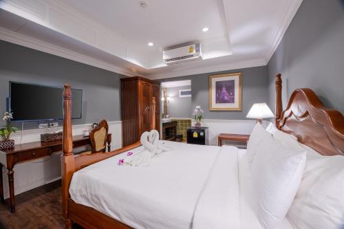 a bedroom with a large white bed with a flat screen tv at The Orchid House 153 in Bangkok