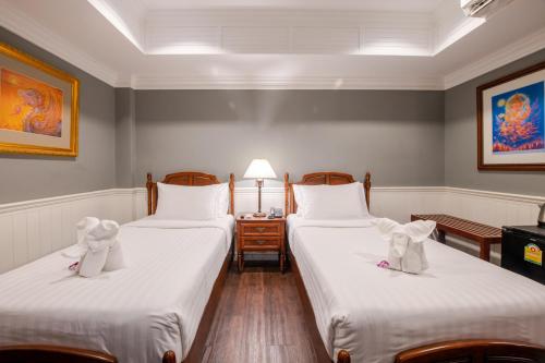 two twin beds in a room with a table at The Orchid House 153 in Bangkok
