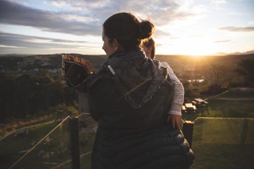 a woman standing on top of a tower looking at the sunset at Garden Route Ilita Lodge in Groot Brak Rivier