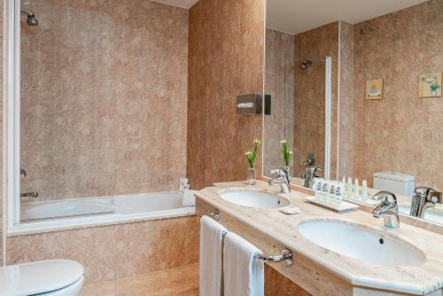 a bathroom with two sinks and a tub at Vincci Ciudad de Salamanca in Salamanca