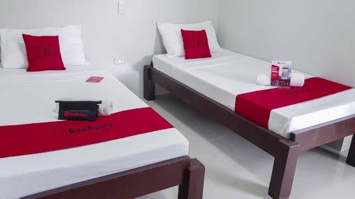 2 bedden met rode kussens in een kamer bij RedDoorz @ VP Inting Street in Tagbilaran-stad