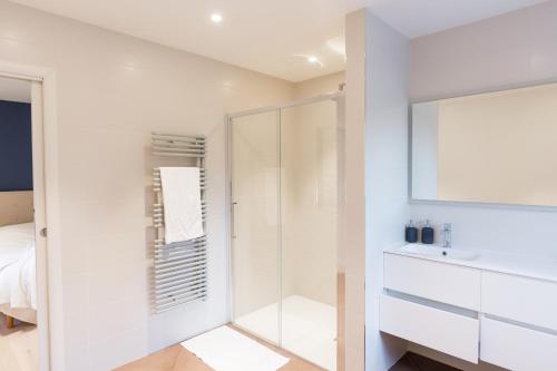 a white bathroom with a shower and a sink at Aux Cortons - Maison avec vue sur le vignoble in Ladoix Serrigny