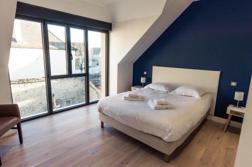 a bedroom with a large bed and large windows at Aux Cortons - Maison avec vue sur le vignoble in Ladoix Serrigny