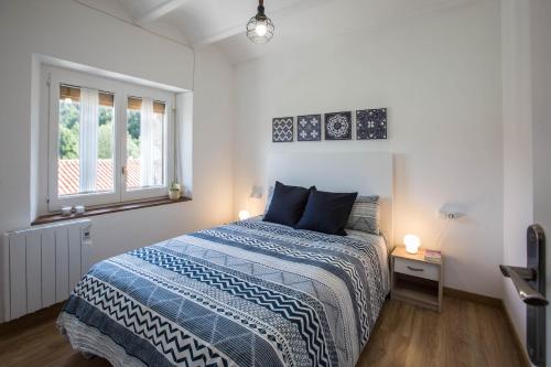1 dormitorio con 1 cama con edredón azul y ventana en Can Botey, en Ripoll
