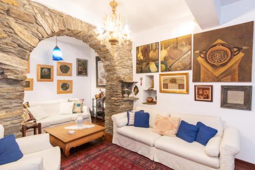 a living room with white furniture and a stone wall at Gladiolus House - Tinos in Tzádhos