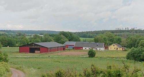 a red barn in a field next to a farm at Borängs Gård in Ullared