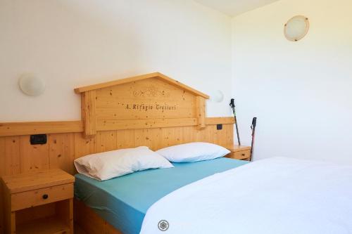 a bedroom with a bed with a wooden headboard at Albergo Rifugio Graziani in Brentonico