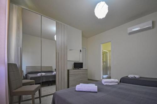 a bedroom with two beds and a chair and a mirror at Hotel La Pineta in Marina di Carrara