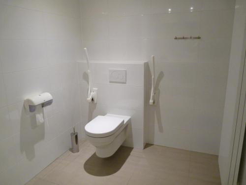 a white bathroom with a toilet in a stall at Hotel Au Prince Royal in Leopoldsburg