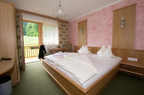 ein Schlafzimmer mit einem großen Bett und einem Fenster in der Unterkunft Hotel-Pension Birkenhof in Kötschach