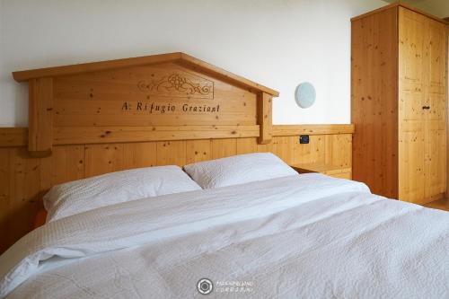 a bedroom with a large bed with a wooden headboard at Albergo Rifugio Graziani in Brentonico