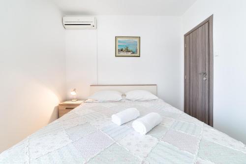ein weißes Schlafzimmer mit einem großen Bett mit zwei Kissen in der Unterkunft Apartment Luna Tribunj in Tribunj