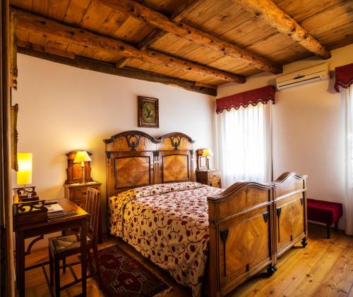 Un dormitorio con una gran cama de madera y una mesa. en B&B Gastaldo di Rolle, en Cison di Valmarino