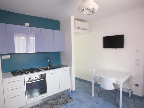 a kitchen with white cabinets and a table and a sink at Casa Vacanze Baia Garagliano in Scario