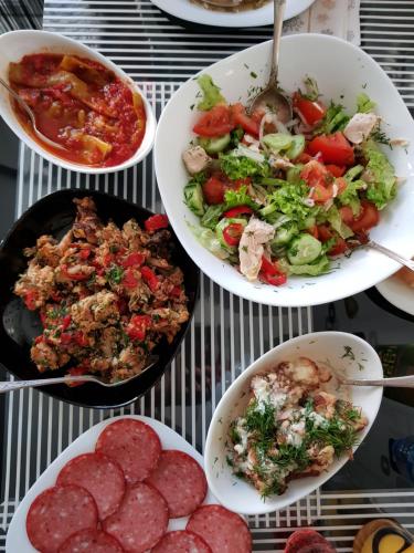 Una mesa cubierta con platos de comida con carne y verduras. en Домик у Куры, en Tiflis