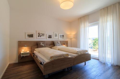 - une chambre avec un grand lit et une grande fenêtre dans l'établissement AusZeit, à Sankt Georgen im Schwarzwald
