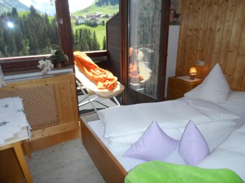 a bedroom with a bed with purple pillows and a window at Haus Brunneck in Warth am Arlberg