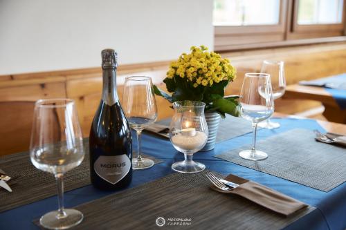 a bottle of wine sitting on a table with wine glasses at Albergo Rifugio Graziani in Brentonico