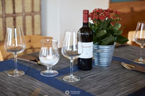 a bottle of wine and three wine glasses on a table at Albergo Rifugio Graziani in Brentonico