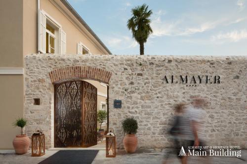 uma mulher passa por uma porta para um edifício de homens em Almayer Art & Heritage Hotel and Dépendance em Zadar