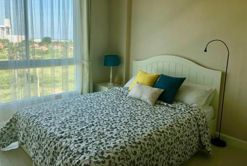 a bedroom with a large bed with pillows and a window at Seaview Apartment at The Energy in Cha Am