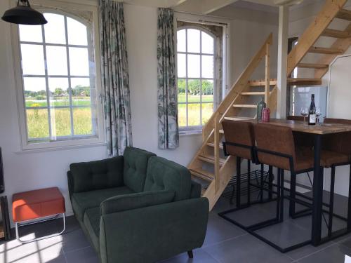 a living room with a green couch and a wooden table at Vakantiewoning Het Gemaal in Oostwold