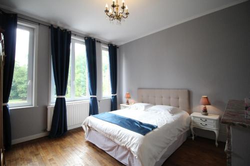 a bedroom with a bed and a chandelier and windows at Bed & Breakfast au Château de Martinsart in Mesnil-Martinsart