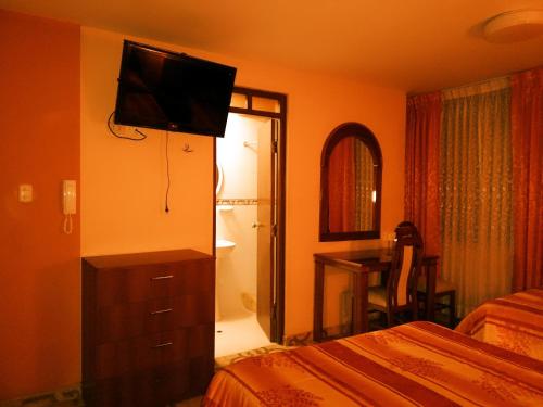 ein Schlafzimmer mit einem Bett und einem TV an der Wand in der Unterkunft Hostal Estrellita Dorada in Tacna