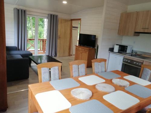 a kitchen and living room with a table and chairs at Domek letniskowy - czerwony całoroczny in Stegers