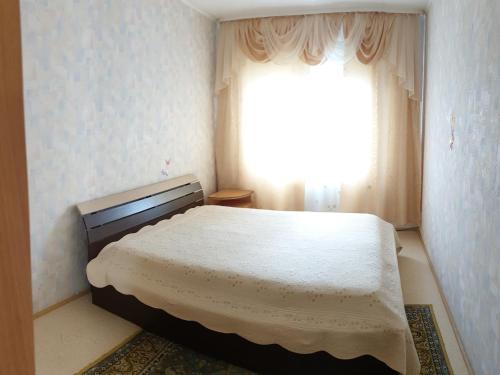 a bedroom with a bed in front of a window at Apartment 6 Mikrorayon in Kurgan