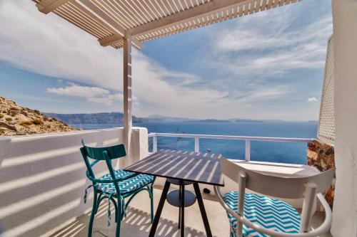 a dining room table with a balcony overlooking the ocean at Armeni Village in Oia