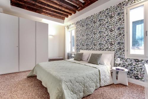 Rugabella Rialto Deluxe في البندقية: غرفة نوم بسرير في غرفة بجدار