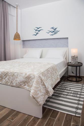 a white bedroom with a white bed and a table at Elenis Philoxenia in Ixia