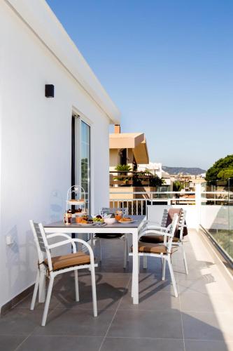 a white dining table and chairs on a balcony at Elenis Philoxenia in Ixia