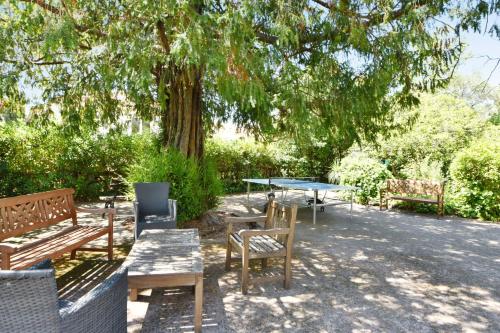 a group of benches and tables under a tree at Zenitude Hôtel-Résidences Le Cannet in Le Cannet