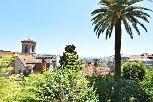 a palm tree and a church in a city at Zenitude Hôtel-Résidences Le Cannet in Le Cannet