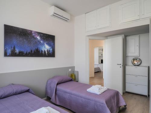 een slaapkamer met 2 bedden en een schilderij aan de muur bij Le case sul parco in La Spezia