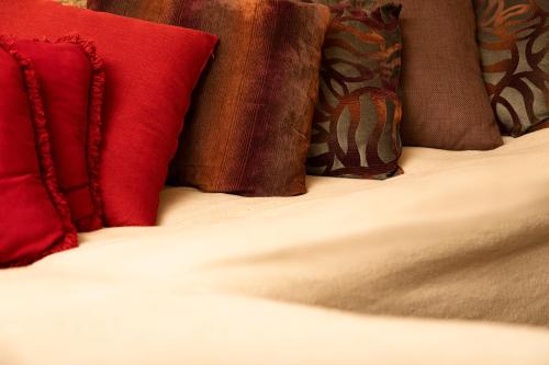 a bed with red and brown pillows on it at Salamiou Stone House in Paphos City