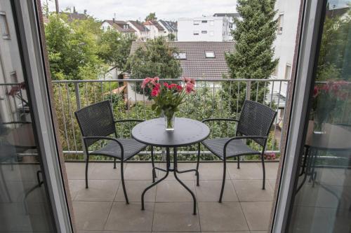 a table with chairs and a vase of flowers on a balcony at Hayta Hotel Stuttgart Airport Messe in Filderstadt