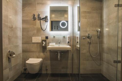 a bathroom with a toilet and a sink and a shower at Hayta Hotel Stuttgart Airport Messe in Filderstadt