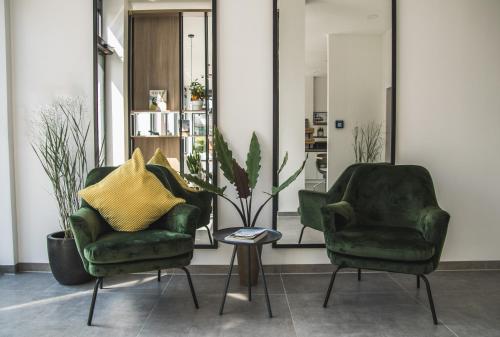 two green chairs and a table in a room at Hayta Hotel Stuttgart Airport Messe in Filderstadt